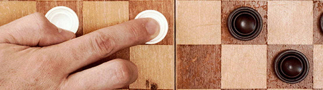 a hand moving checkers across a board