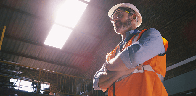 Man in a safety vest and a hard hat with arms crossed