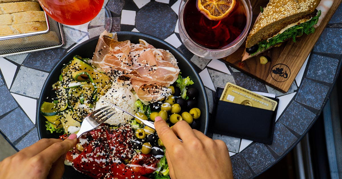 Plate of food on a table with an open wallet and a credit card sitting next to it