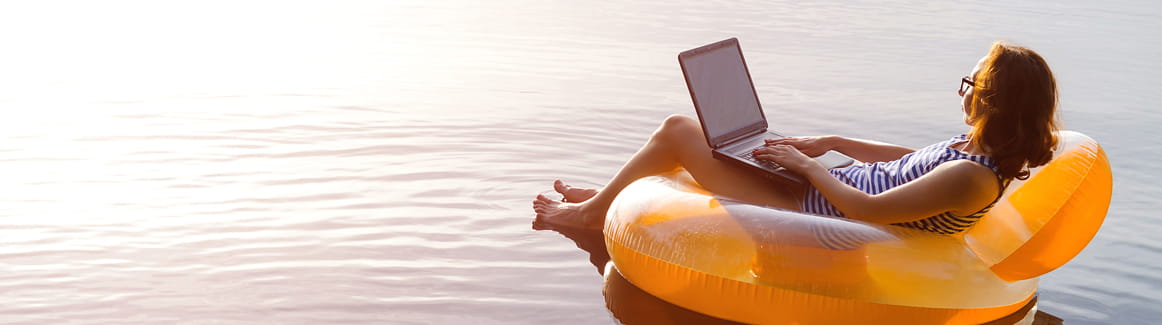Woman on a float in a lake using a laptop computer