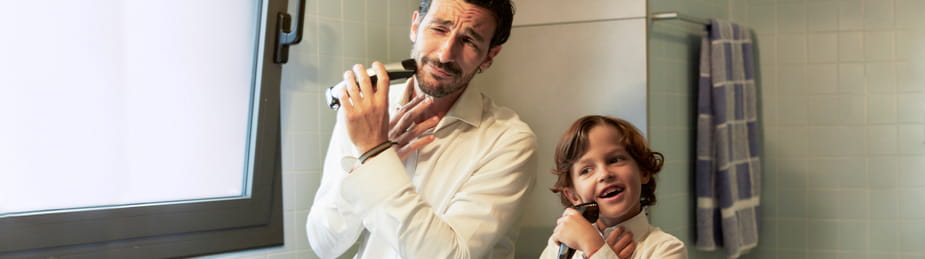 Man shaving while young son pretends to shave alongside him