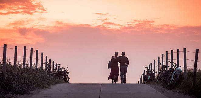 Two people walking down a path into the sunset