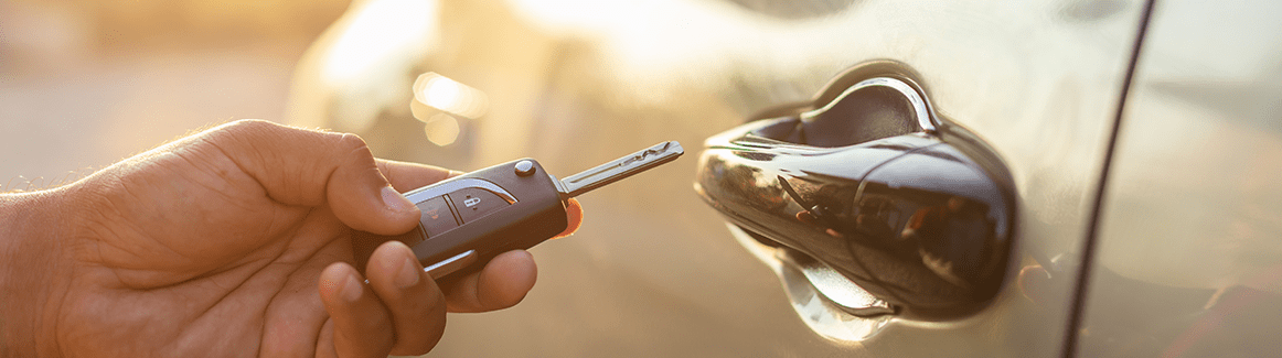 Person holding keys next to a car door handle
