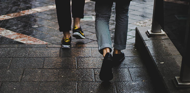Two people walking on a wet brick road